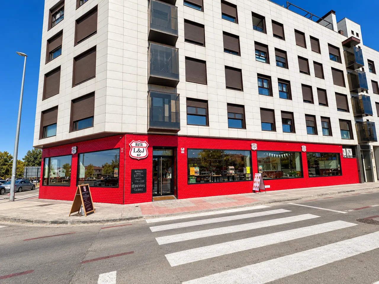 Edificio en esquina con la fachada roja de L&J Ruta 67 y paso de cebra